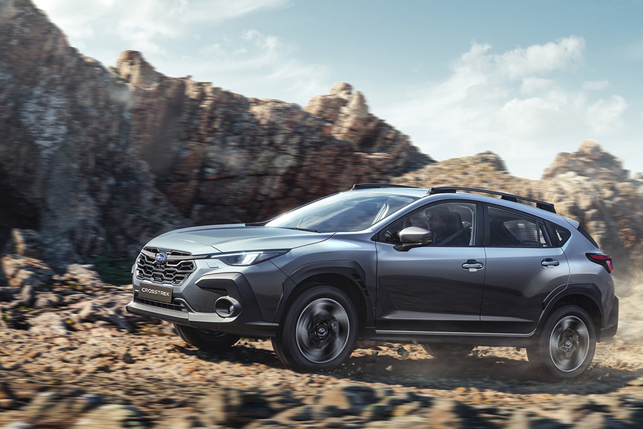 Subaru Crosstrek sõidab kruusateel, tolmupilved keerlevad auto taga.